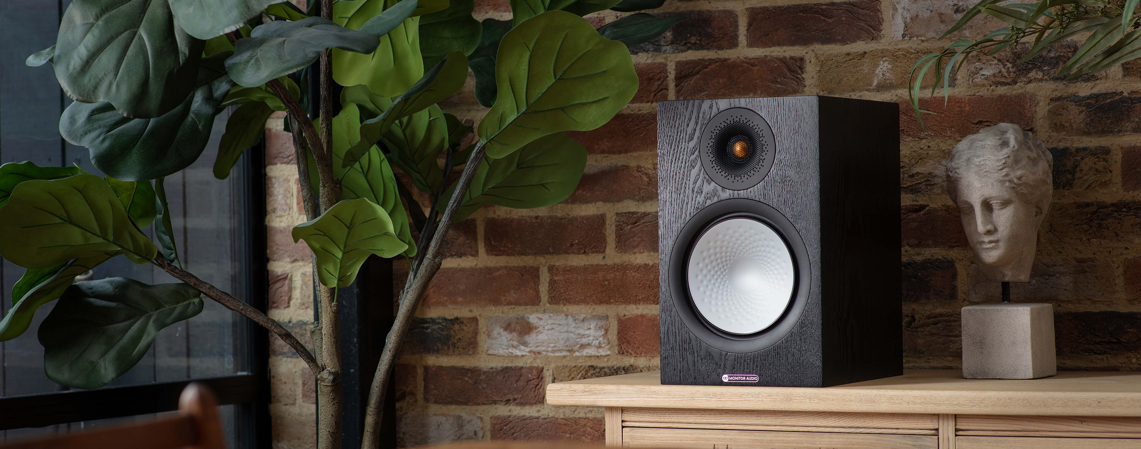 Lifestyle shot of Monitor Audio's Silver 100 7G, in a black oak finish.